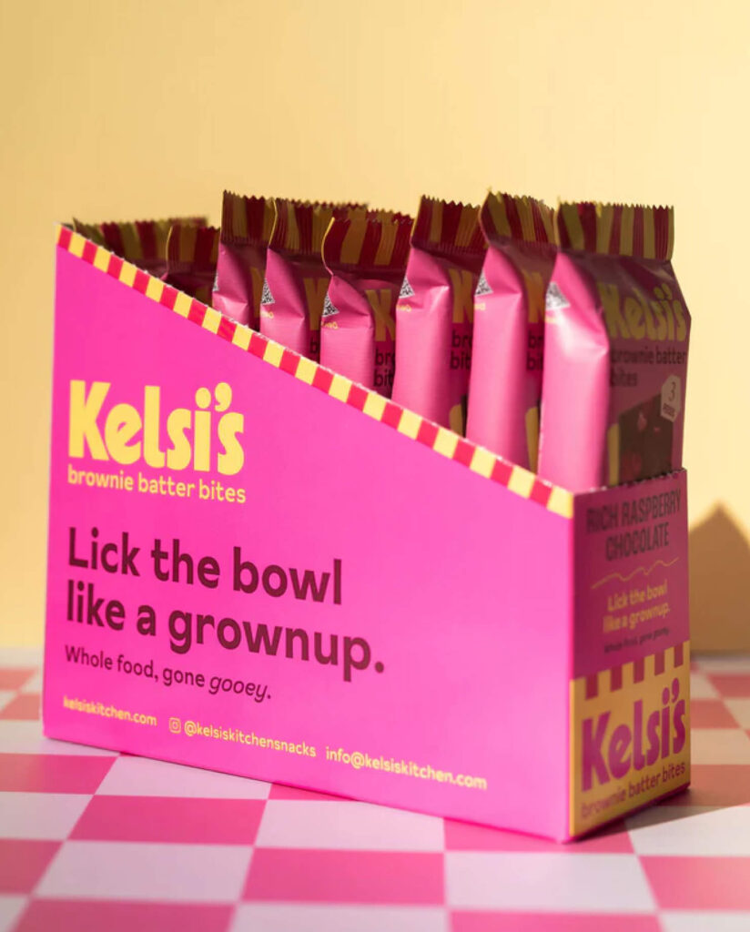 Kelsi's brownie batter bites in a pink and yellow box over top of a checkered table.